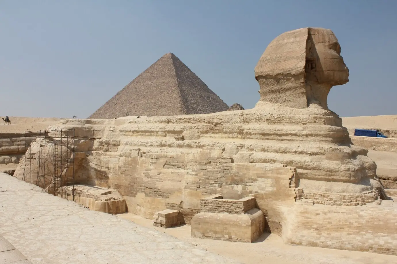 Aufnahme einer historischen Sphinx inmitten einer typischen ägyptischen Szenerie unter klarem Himmel.