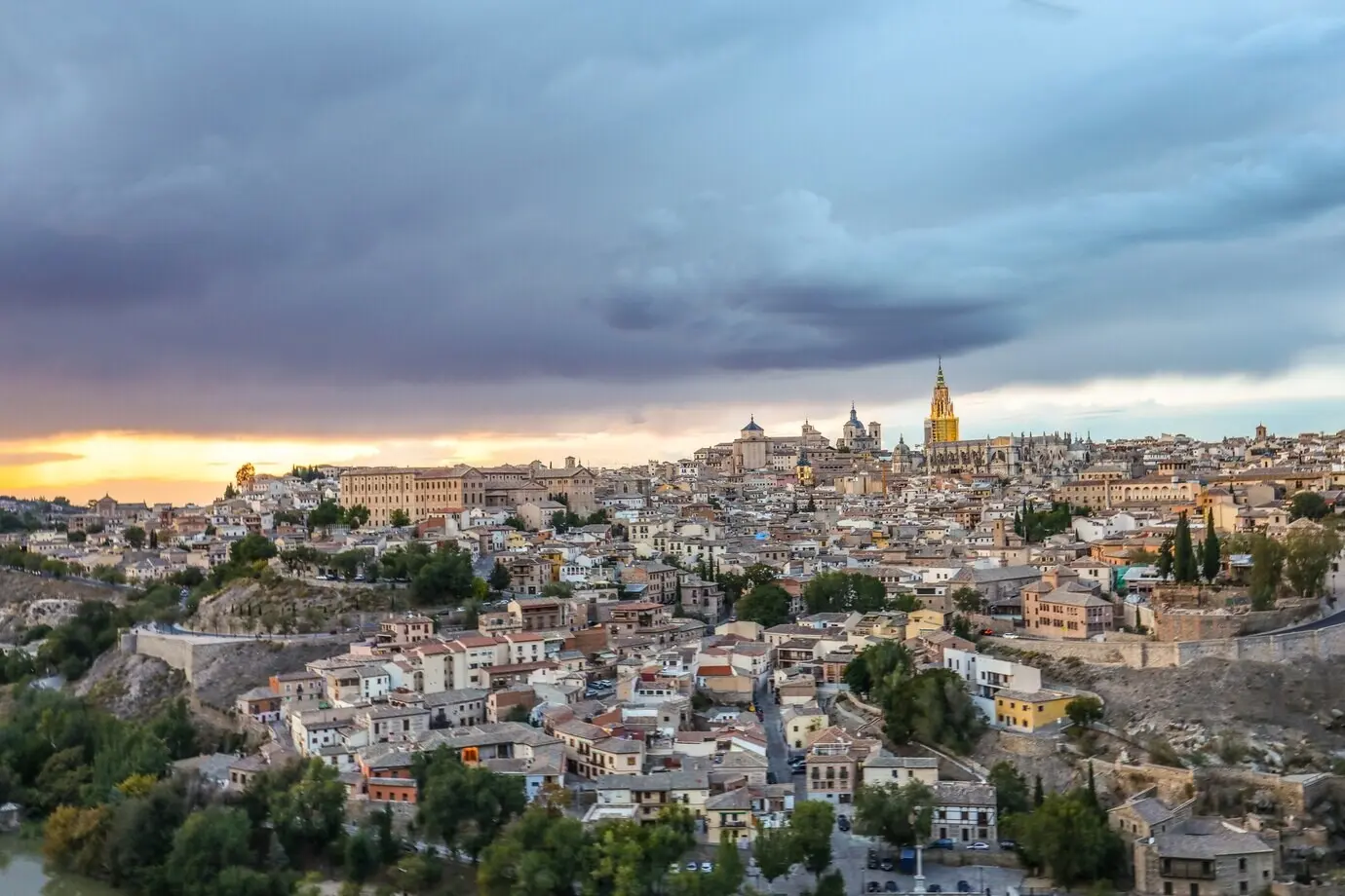 Blick aus der Vogelperspektive auf die Stadt Toledo in Spanien unter einem dunklen, wolkenverhangenen Himmel.